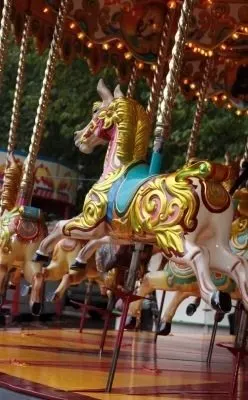 Children ride the colorful carousel horses at the outdoor amusement park.
