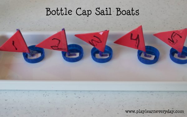 A group of carmine origami bottle cap sail boats are floating in a pool of water.