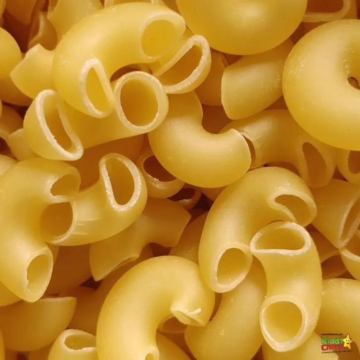 A bowl of steaming pasta is being served on a plate with a side of vegetables.