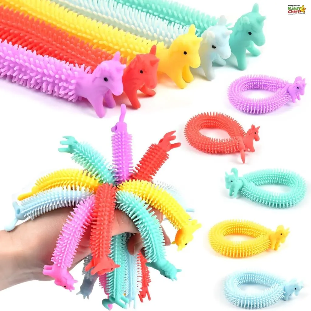 A person's hand is covered with brightly colored, spiky unicorn bracelets. Loose bracelets and unicorns arranged in the background on a white surface.