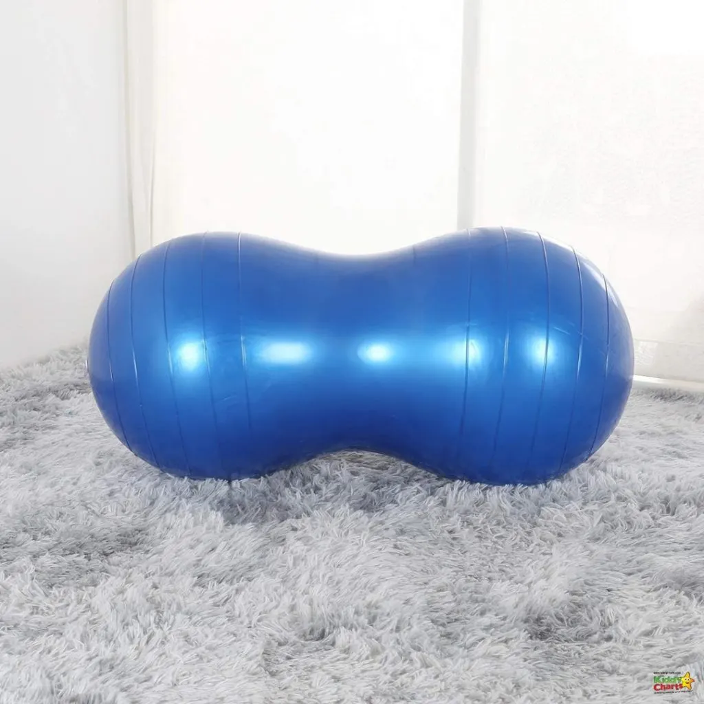 A bright blue, peanut-shaped fitness ball rests on a soft, shaggy gray carpet against a white wall, possibly used for exercise or physical therapy.