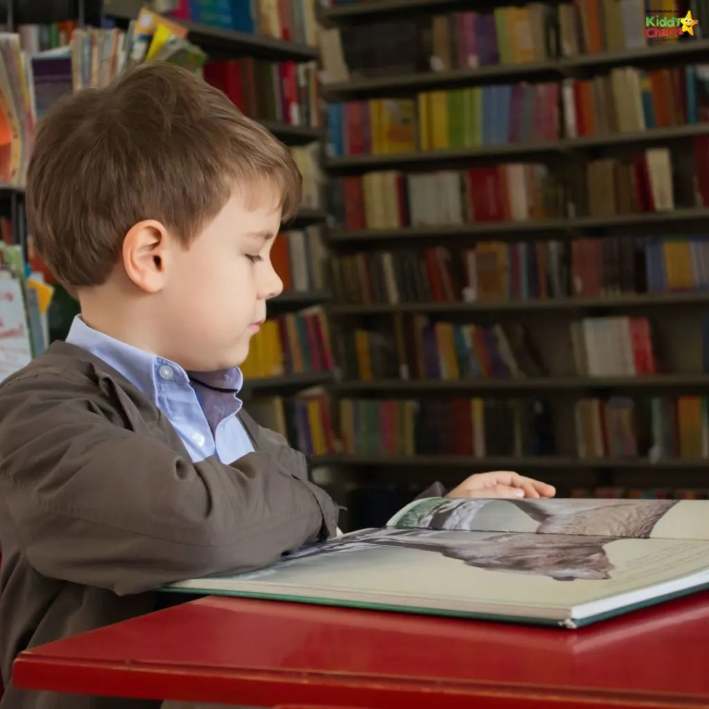 A child is engrossed in reading a large book at a red table, with colorful bookshelves filled with books in the background.