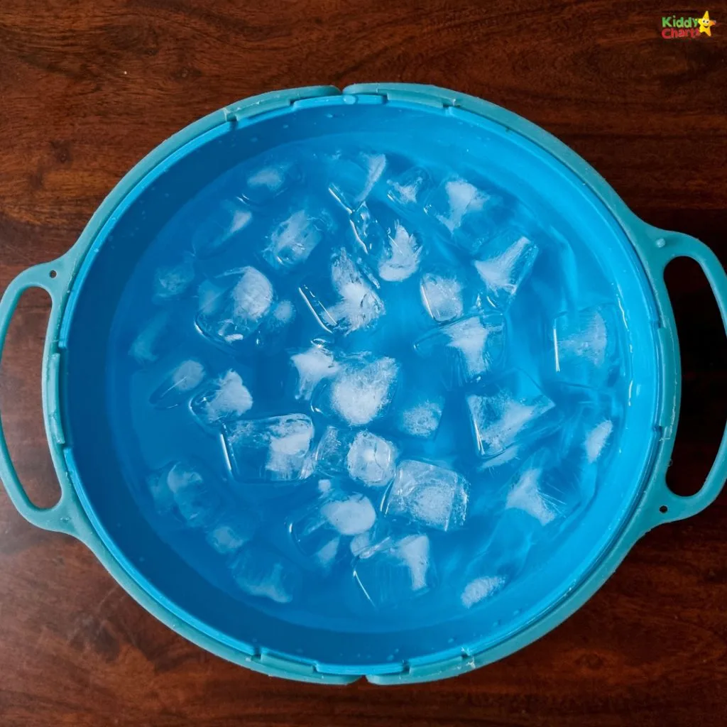 A blue circular basin filled with water and ice cubes, placed on a wooden surface. It exudes a cool, refreshing ambiance.