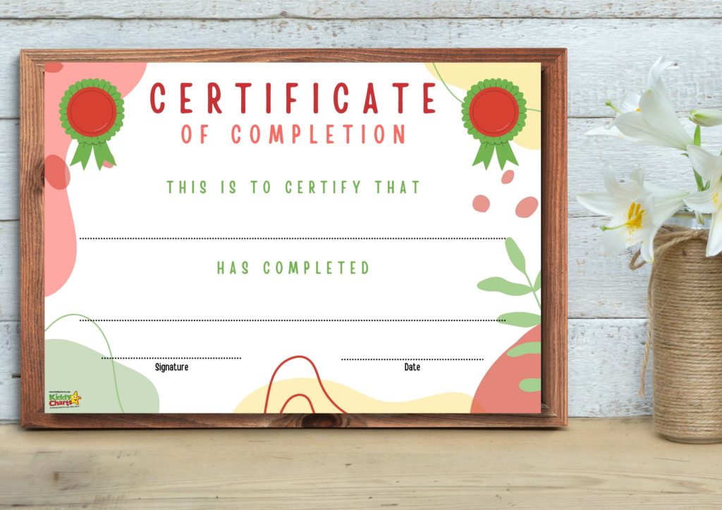 A framed certificate of completion with a colorful, playful design rests on a wooden surface beside a vase with white flowers.