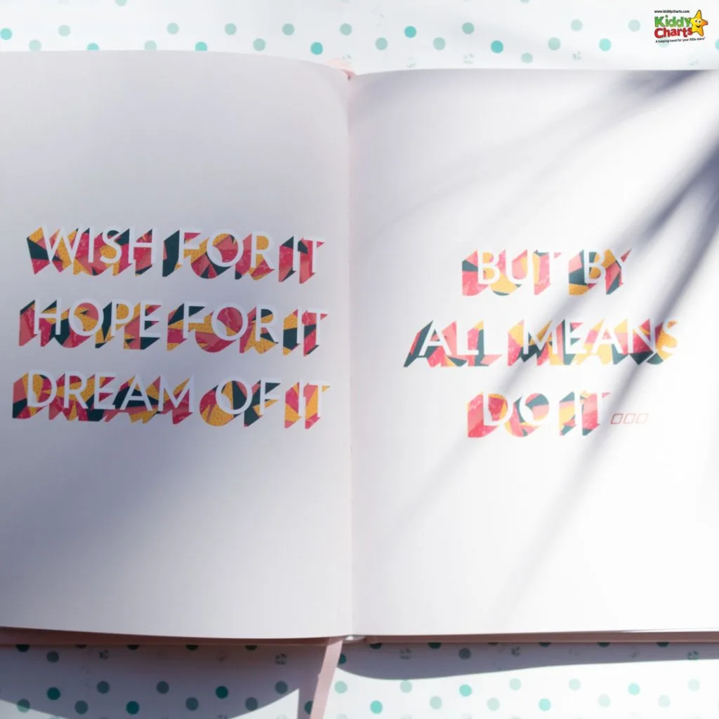 An open book with colorful typographic art reads “WISH FOR IT HOPE FOR IT DREAM OF IT BUT BY ALL MEANS DO IT” against a dotted background.