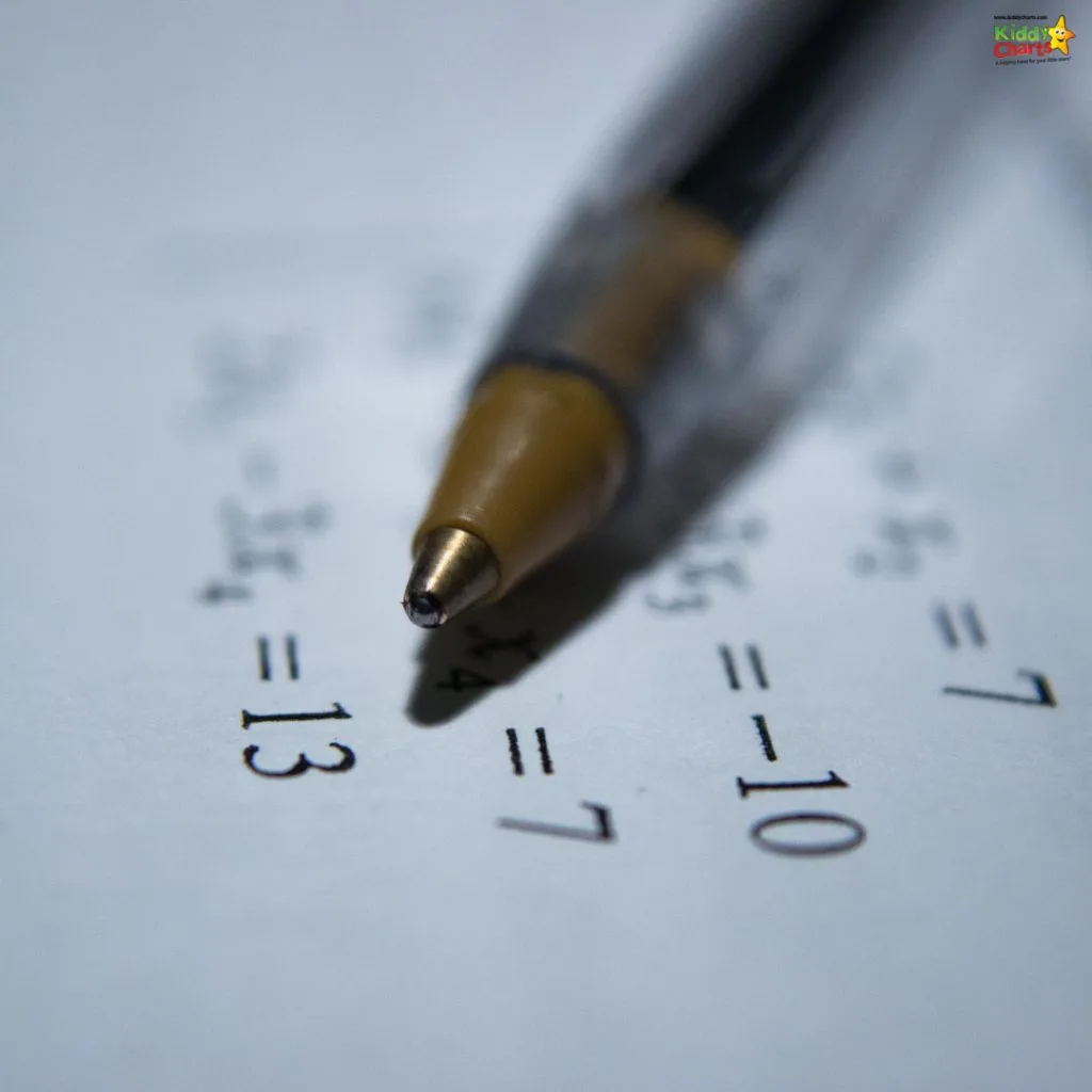 A close-up image of a ballpoint pen tip on a page with printed mathematics equations, focusing sharply on the pen with a blurred background.